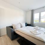 Schlafzimmer mit Schlafcouch, Fenster und Holzboden.