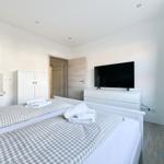 Zwei Betten mit Handtüchern, Fernseher und Kleiderschrank im Schlafzimmer.