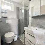 Badezimmer mit Dusche, Waschbecken und Toilette. Graue Wände und weißes Badmöbel.