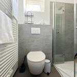 Badezimmer mit Dusche, Toilette und Handtuchheizung.