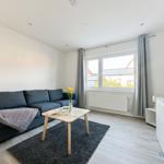 Wohnzimmer mit Sofa, Tisch und TV. Fenster mit Vorhängen. Teppich und Holzboden.