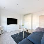 Wohnzimmer mit Sofa, TV und Kleiderschrank.