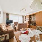 Wohn- und Essbereich mit Sofa, TV und Esstisch mit Tischwäsche.