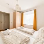 Zwei Betten mit karierten Bettwäschen, Fenster mit gelben Vorhängen und Holzschrank.