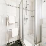 Bad mit Dusche, Handtuchhalter und Toilettenpapier.