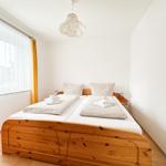 Schlafzimmer mit Holzbett, Fenster und Deckenleuchte.