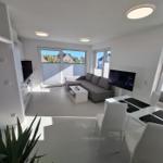 Wohn- und Essbereich mit Sofa, TV und großem Fenster. Moderne Einrichtung.