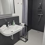 Badezimmer mit Dusche, Waschbecken und Spiegel.