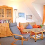 Wohnzimmer mit Sofa, Sessel und Holzmöbel. Fenster mit orangefarbenen Vorhängen.