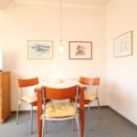 Esszimmer mit runden Tisch und vier Stühlen, Wandbilder und Pendelleuchte.