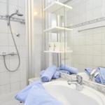 Badezimmer mit Dusche, Waschbecken und blauen Handtüchern.