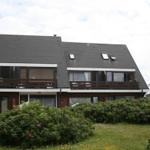 Zweistöckiges Haus mit Balkonen und begrüntem Vorgarten