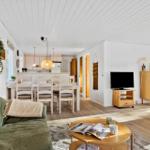 Wohnzimmer mit Sofa, Esstisch und Küche im Hintergrund.