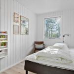 Schlafzimmer mit Bett, Stuhl, Fenster und Bücherregal an der Wand.