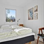 Schlafzimmer mit Bett, Stuhl und Fensterblick auf Wald.