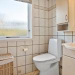 Badezimmer mit Toilette, Waschbecken und Fenster mit beschichtetem Glas.