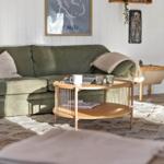 Ein Wohnzimmer mit grünem Sofa, Holztisch und Wandbild.