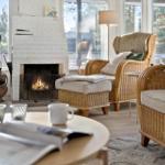 Wohnzimmer mit Kamin, Rattanmöbeln und großem Fensterblick.