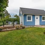 Blauer Holzhaus mit Terrasse, Grill und Garten.
