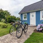 Blau gestrichenes Haus mit weißer Tür und Fenstern. Zwei Fahrräder stehen auf dem Kiesweg.