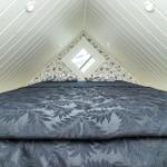 Schlafzimmer mit Dachschrägen, Dachfenster und gemusterter Bettwäsche.