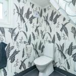 Badezimmer mit Toilette, Dusche und floraler Tapete