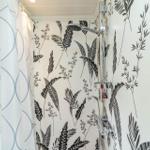Dusche mit floraler Wandtapete und Duschvorhang.