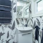 Badezimmer mit Waschbecken, Spiegelschrank und Handtuchhalter an floral gemusterten Wänden.