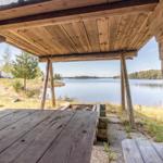 Holzterrasse mit Tisch und Sitzgelegenheit am See.