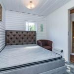 Schlafzimmer mit Bett, Sessel und Sauna im Hintergrund.