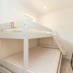 Zimmer mit Doppelstockbett, weiß lackiert, mit Matratzen und Leiter.