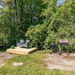 Holzterrasse mit Sitzgruppe und Grill im Wald.