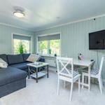 Wohnzimmer mit Sofa, Esstisch und Fernseher an der Wand.