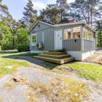 Holzhaus mit Terrasse im Wald. Eingangstreppe und Fenster sichtbar.