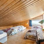 Bedroom with two beds, wood walls, and sloped ceiling. Window with sea view.