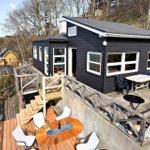 Black house with terrace, tables, and chairs. Wooden terrace with view of surroundings.