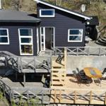Black house with wooden terrace and outdoor seating area.
