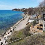 Black house with terrace along coastal path. View of the sea and rock breakwater.