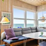 Seating area with sea view, wooden walls and window front.
