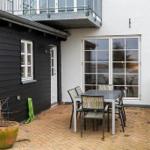 Terrace with table and chairs, black and white house walls, window and plant