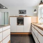 Modern kitchen with white cabinets, wooden surfaces, and built-in cooktop.