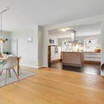 Dining area with table and chairs, kitchen with island and windows.