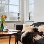 A living room with a dark sofa, wooden table, and windows.