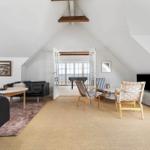 Living area with sofa, chairs, and TV under high ceiling