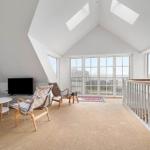 Living room with sloped ceiling, TV, seating, and window wall.