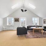 Living room with black sofa, round table, and sloped ceiling.