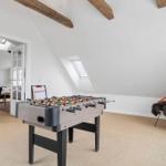Game room with foosball table and chair under sloped ceilings.
