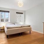 Bedroom with bed, two windows, and hardwood floor.