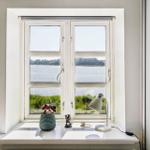 Window with view of water and greenery. On sill: plant, lamp, and decor.