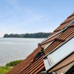 Roof with skylights overlooking calm water and green island.